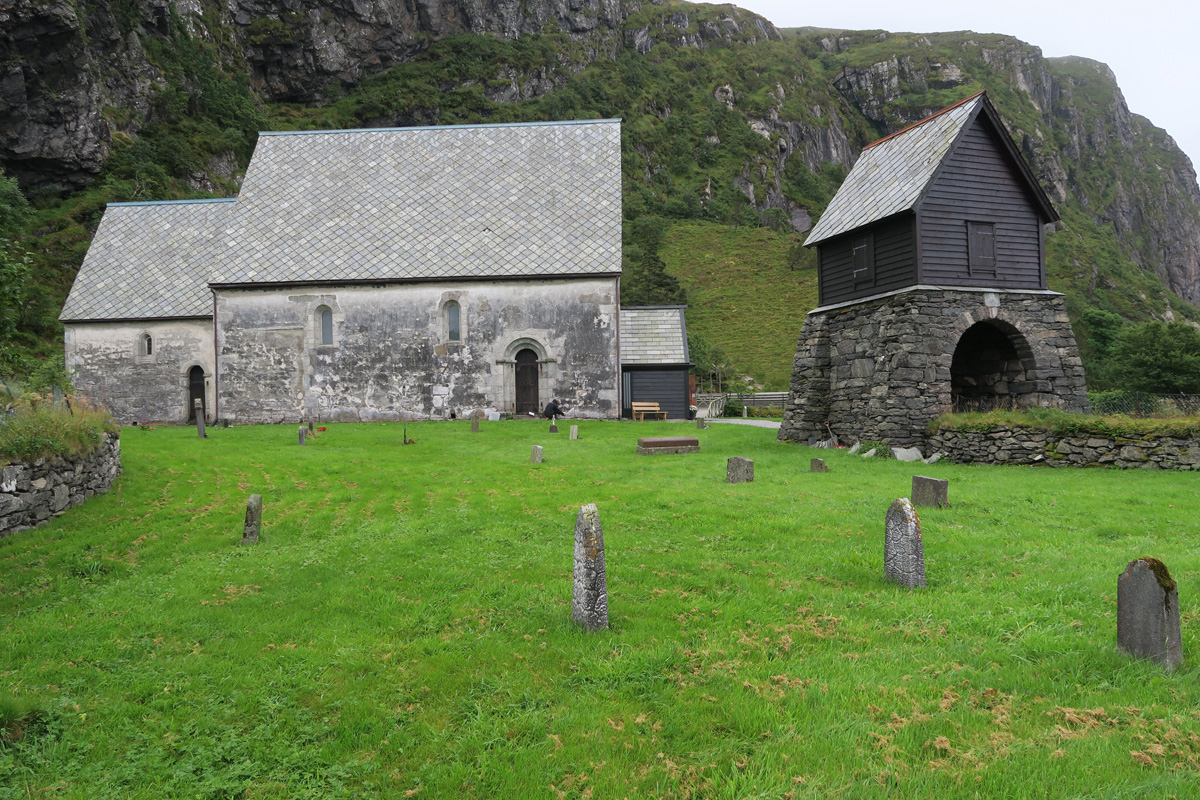 0)	Kinn kyrkje sett fra nord. Pussen faller av, og veggen er sort av algevekst.
