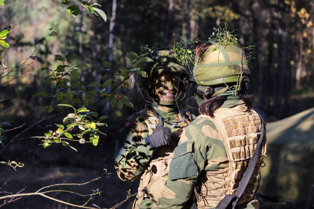 To soldater står i en skog på et øvningsfelt.