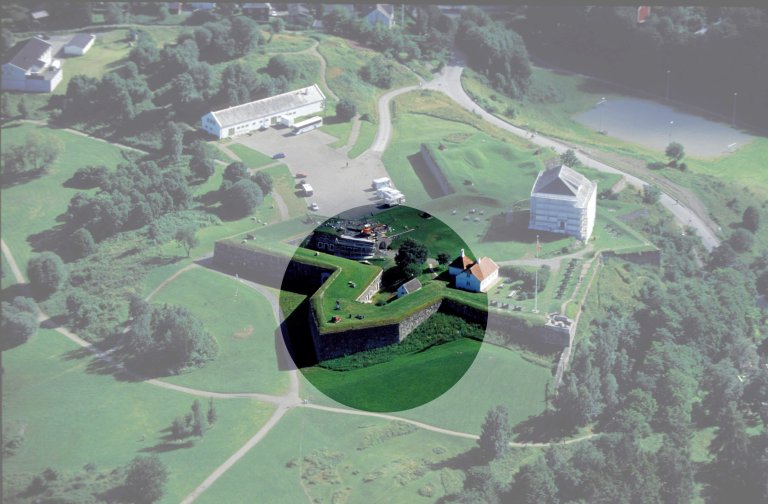 Luftfoto av historisk Kristiansten festning omgitt av grønne marker og trær, med stjerneformet struktur og flere bygninger innenfor murene